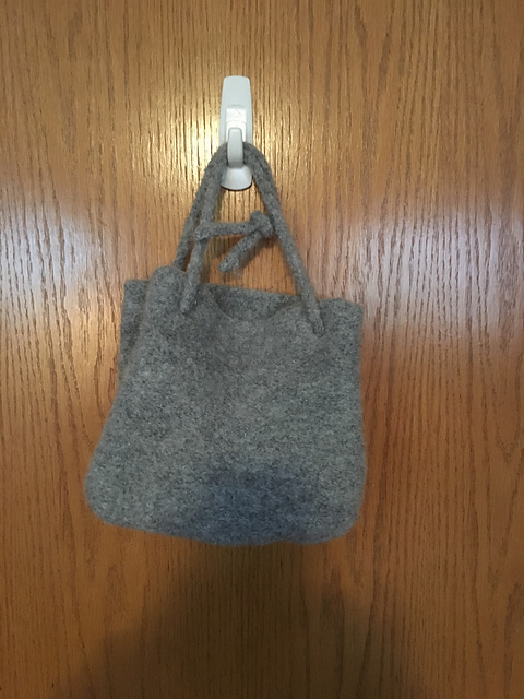 A small tote bag knitted in gray wool yarn that is then felted in a washing machine.