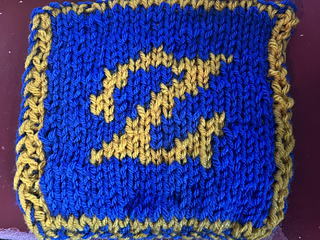 A double-knitted blanket square. This is the front of the square, featuring a styled golden 'Z' on a field of bright blue.