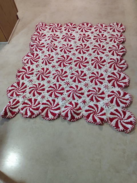 A crocheted blanket in the interlocking method, featuring a peppermint swirl design.