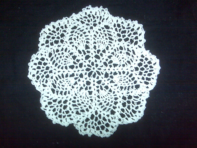 A small crocheted circular doily featuring the popular pineapple stitch.