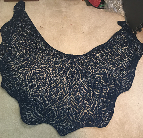 A navy blue crescent shaped shawl with intricate lace and beads.